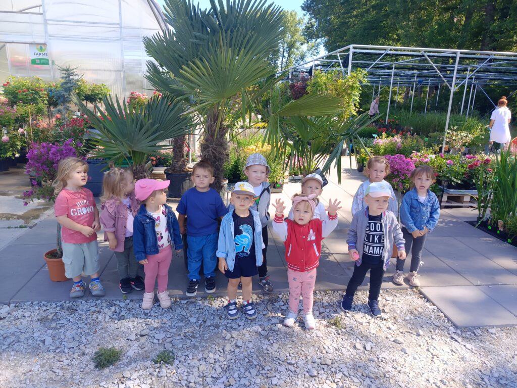 Dzieci stoją pod palmami w doniczkach.